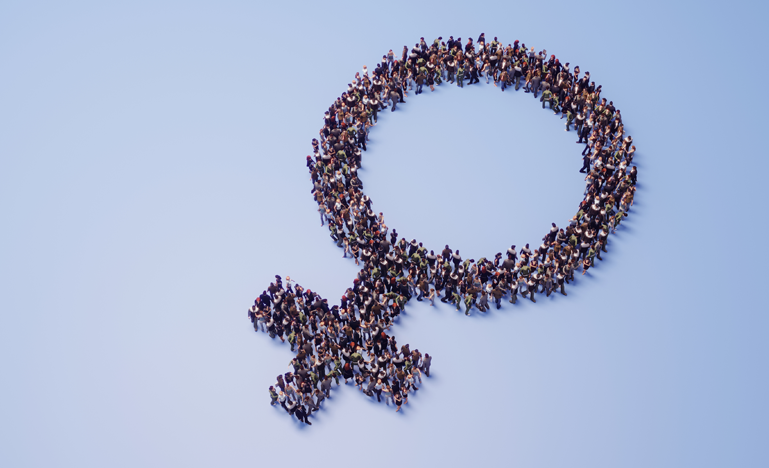 A large group of people standing together to form the shape of a female gender symbol on a light blue background, symbolizing unity and collective identity for women's rights or gender equality.