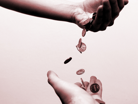 Coins falling between two hands.