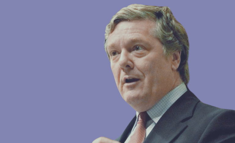 Benoit Pelletier en costume-cravate s'exprimant sur un fond violet.
