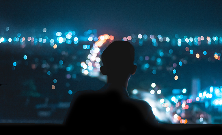 shadowed figure overlooking city lights