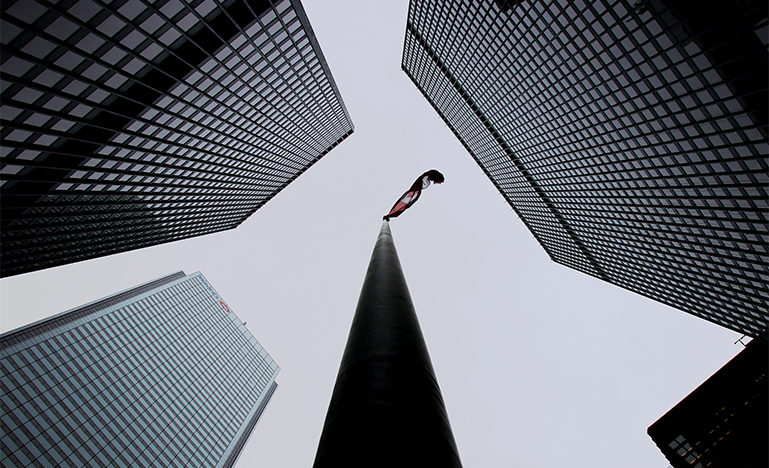 Bottom view of Canada flag on flag pole surrounded by buildings