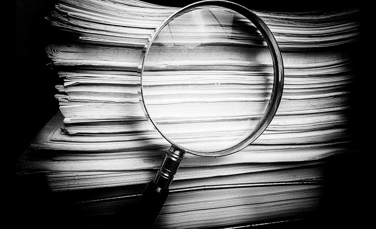 A stack of papers and a magnifying glass