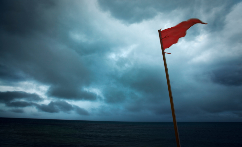 A red flag on a beach by the ocean