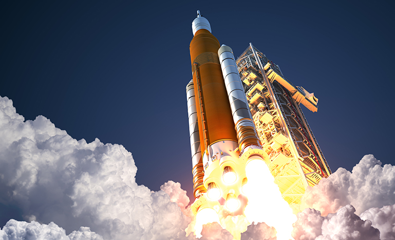 A large rocket launches, surrounded by billowing clouds of smoke and bright flames, against a clear blue sky, conveying power and excitement.