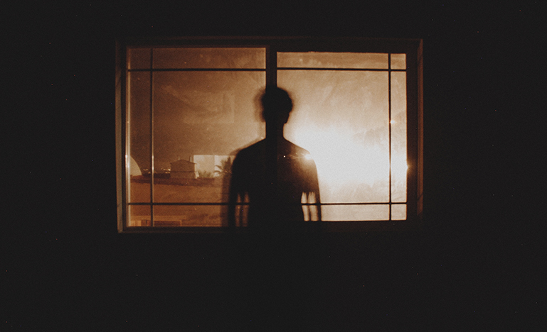 Person in the shadows in front of window