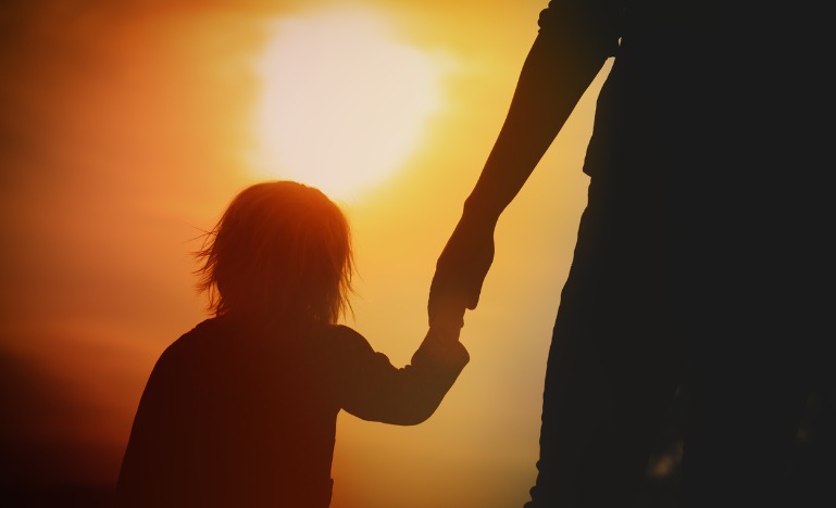 Silhouette of girl holding parent's hand