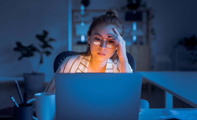 Tired woman at a keyboard in the dark.