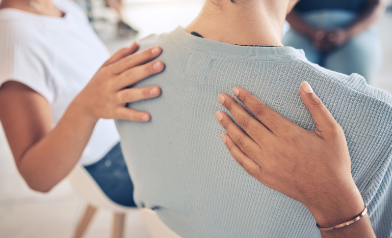 Hands on the back of woman in a restorative justice circle