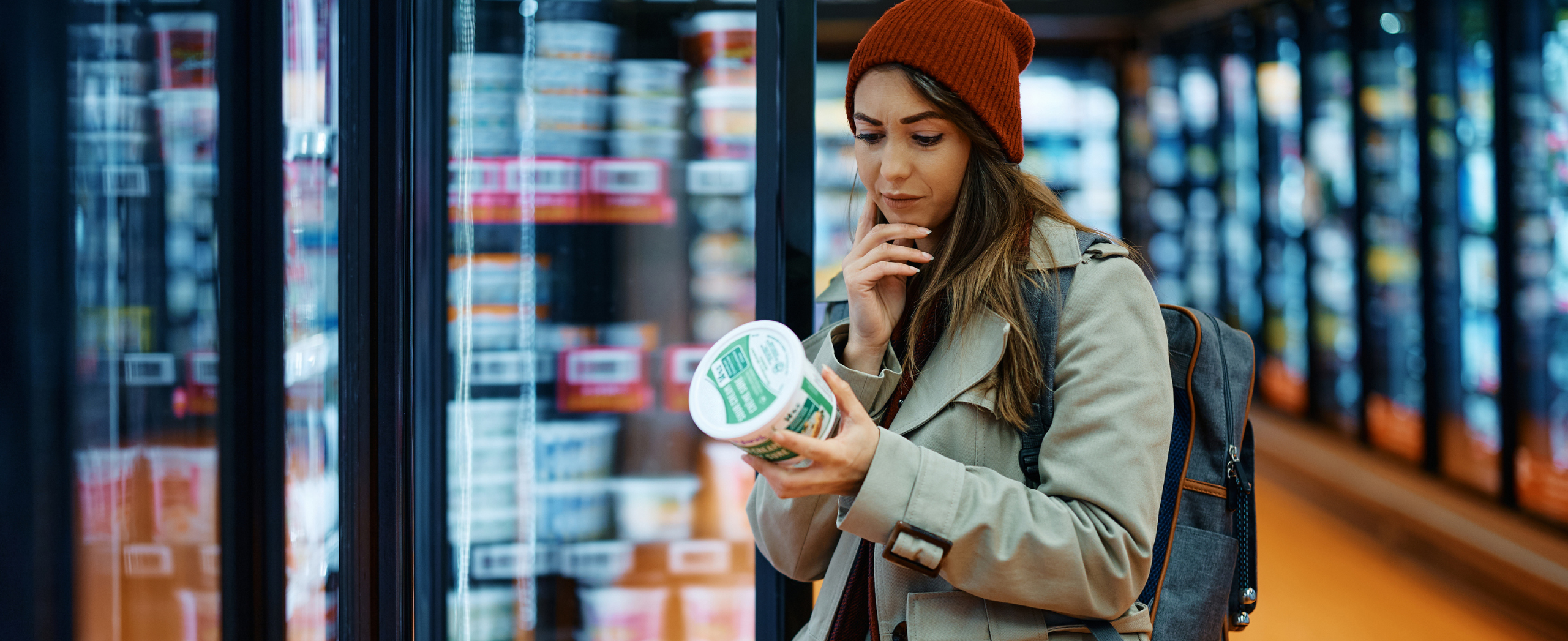Une femme lit une étiquette nutritionnelle en achetant un produit laitier au supermarché