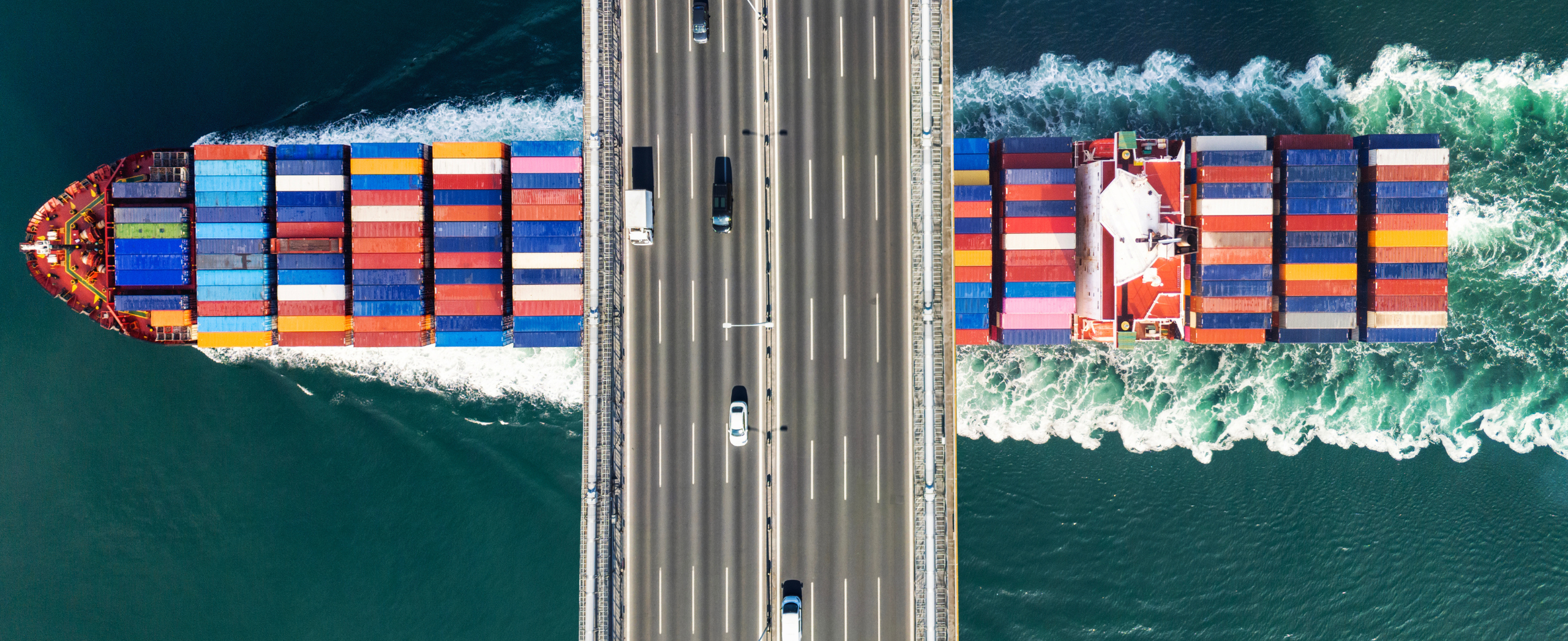 A loaded cargo ship passes beneath a bridge