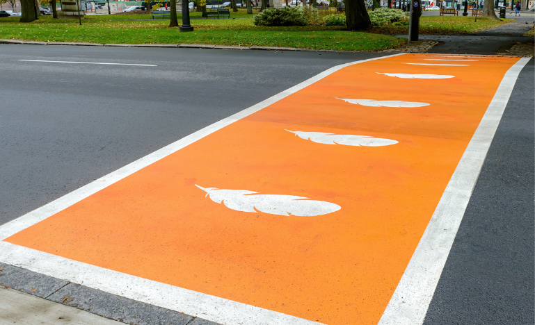 Crosswalk painted orange with white feathers for Truth and Reconciliation