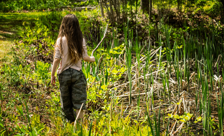 A girl walks along a pond