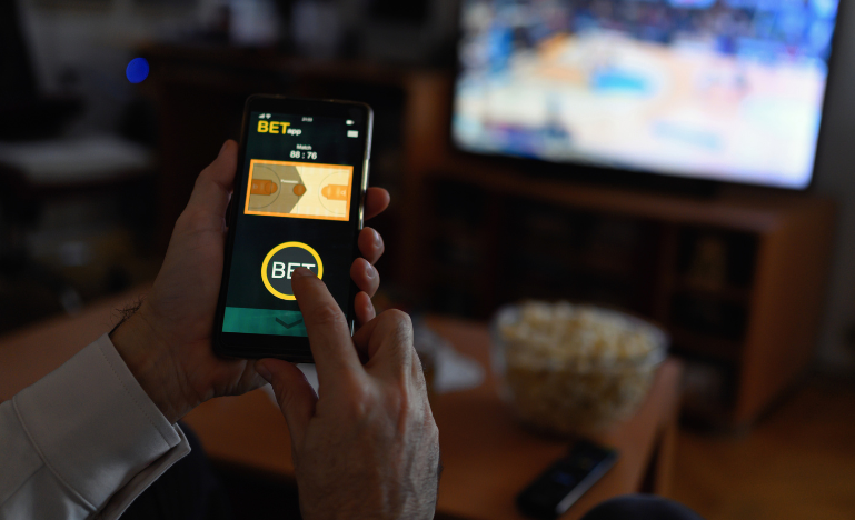 A man bets on his phone while watching a game