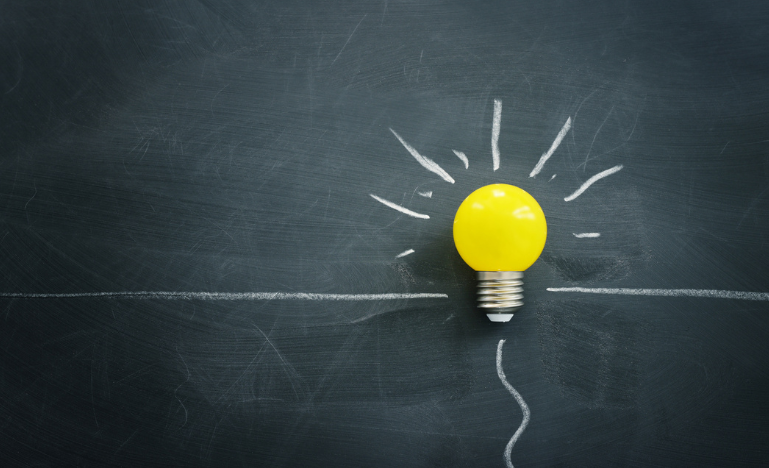 A lightbulb against a chalkboard