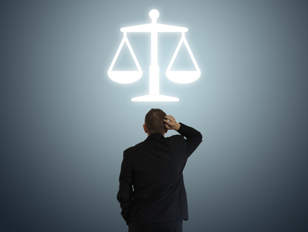 A business lawyer looks up at the scales of justice