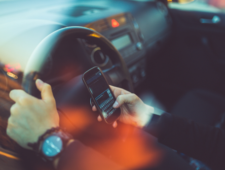 A man uses a cell phone while driving a car