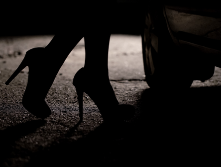 Silhouette de jambes féminines en talons hauts venant vers la voiture