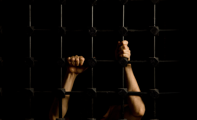 Hands of a prisoner through cell bars