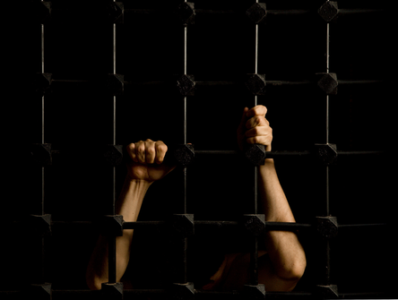 Hands of a prisoner through cell bars